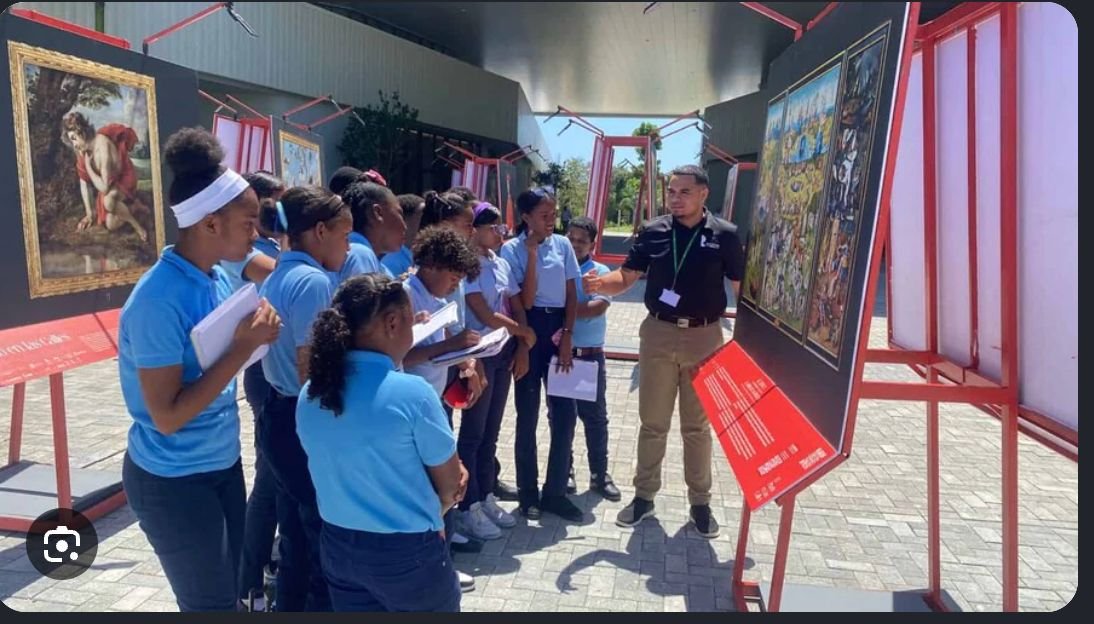 Grupo de personas en una visita guiada educativa en La Fiesta de la Cosecha observando una exposición cultural.